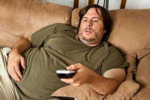 A man living a sedentary lifestyle by spending his day sitting and watching TV all through.